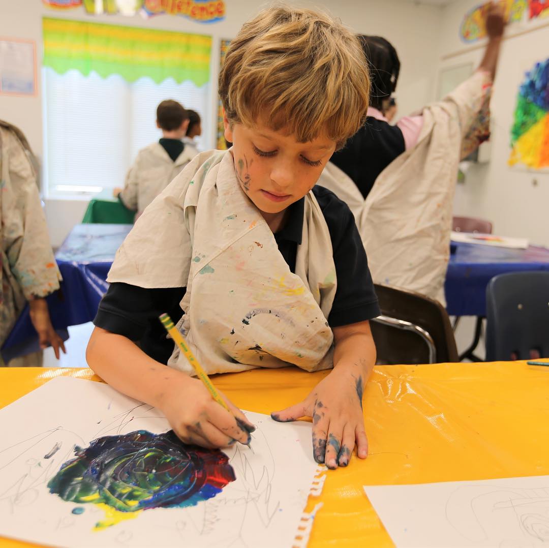 Sometimes the paint ends up on the artist as this ICS student makes a color wheel during art class