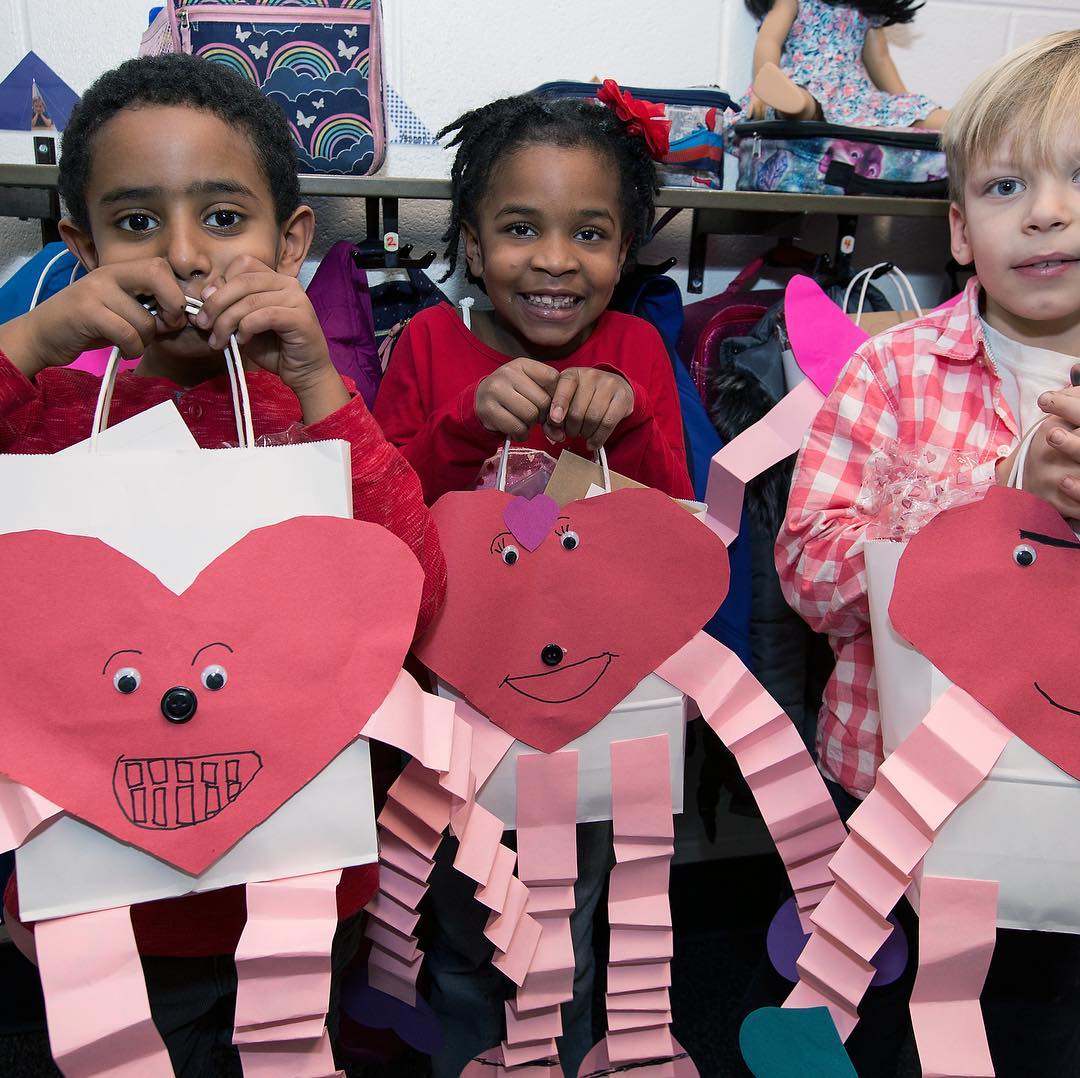 Some friends show off their Valentine’s Day bags made in their 1A class